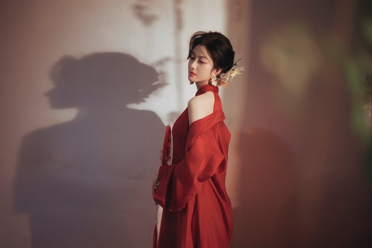 Artistic portrait of a woman in a red dress with a shadow cast on the wall.