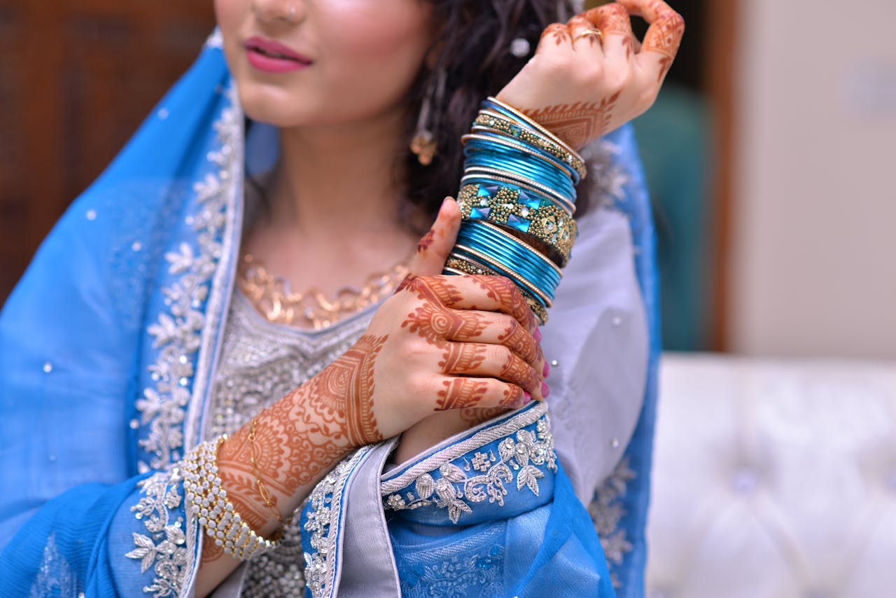 A bride showcases intricate henna designs and vibrant jewelry in traditional attire.
